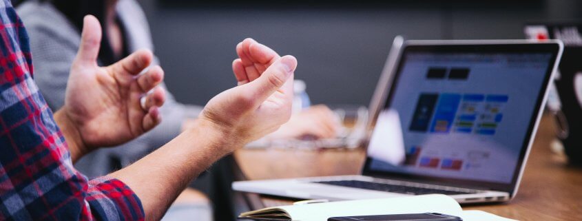 Man in front of computer with smartphone on desk